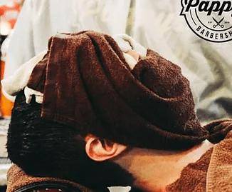 Client relaxing under hot towels during a straight razor shave